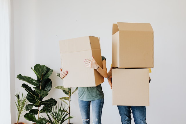 two people holding moving boxes in front of their faces